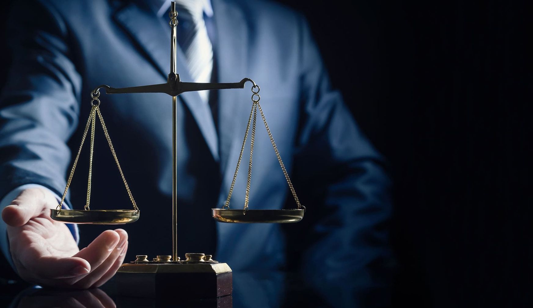 Eine Person im Anzug und eine goldene Waage im Vordergrund